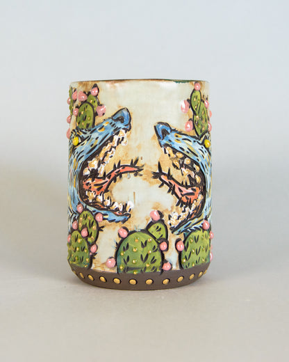 Ceramic tumbler with painted desert scene featuring coyotes and cacti on a white background