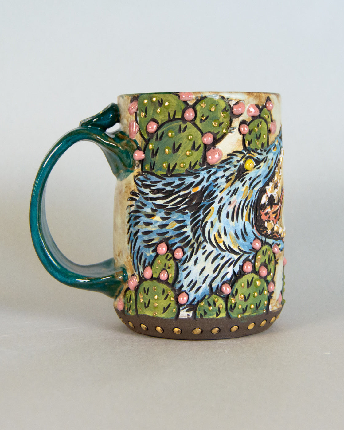 Ceramic mug with a coyote and cactus design on a plain background