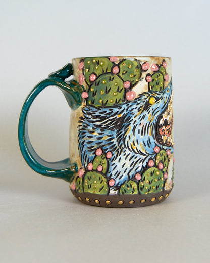 Ceramic mug with a coyote and cactus design on a plain background