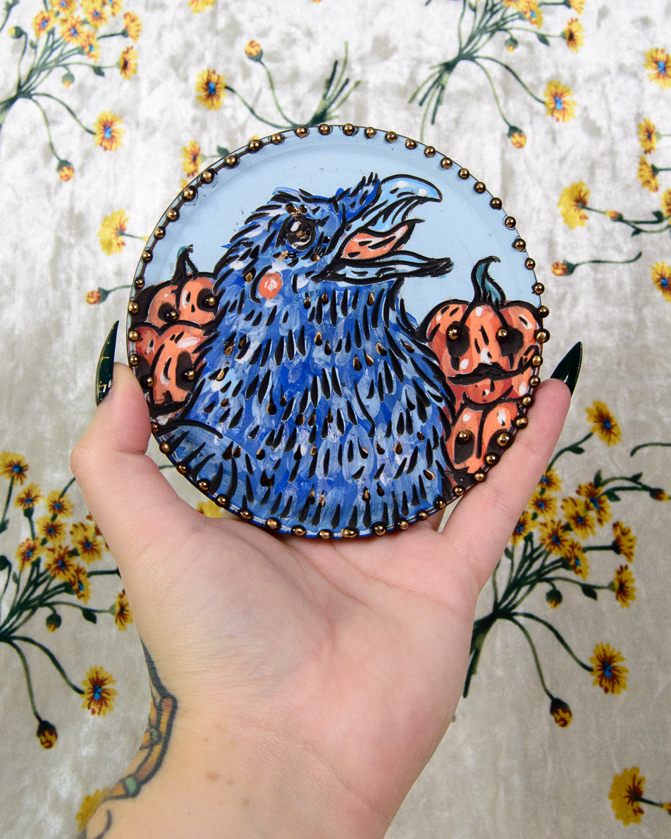 Ceramic coaster of a cartoon blue crow and pumpkin design