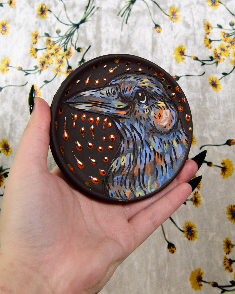 Black stoneware ceramic coaster with a hand painted bird design