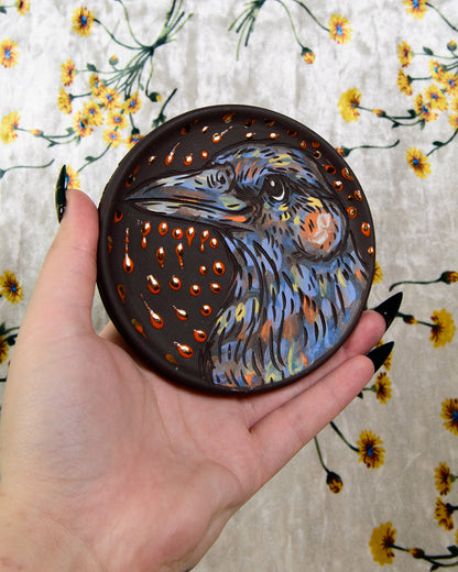 Black stoneware ceramic coaster with a hand painted bird design