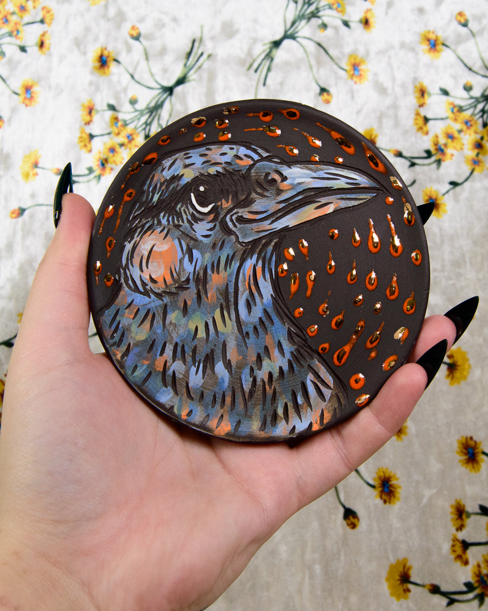 Black stoneware ceramic coaster with a crow design and gold details