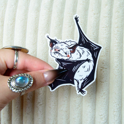 A sticker of a cute bat dancing ballet with pink accents against a beige background