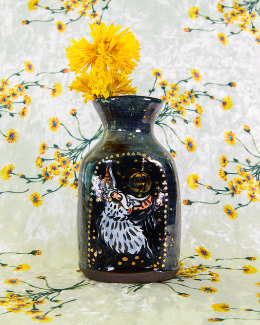 Decorative vase with a painted design of a disco dancing bat, filled with yellow flowers, on a floral background.