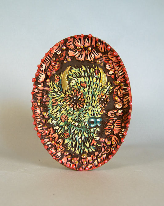 Decorative ceramic plate with a colorful, intricate bison design on a light gray background