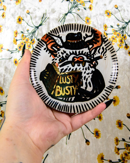 ceramic coaster with a cute detective bat design and a book that says "lusty busty"