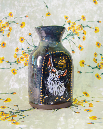 Decorative vase with a painted design of a bat on a floral background