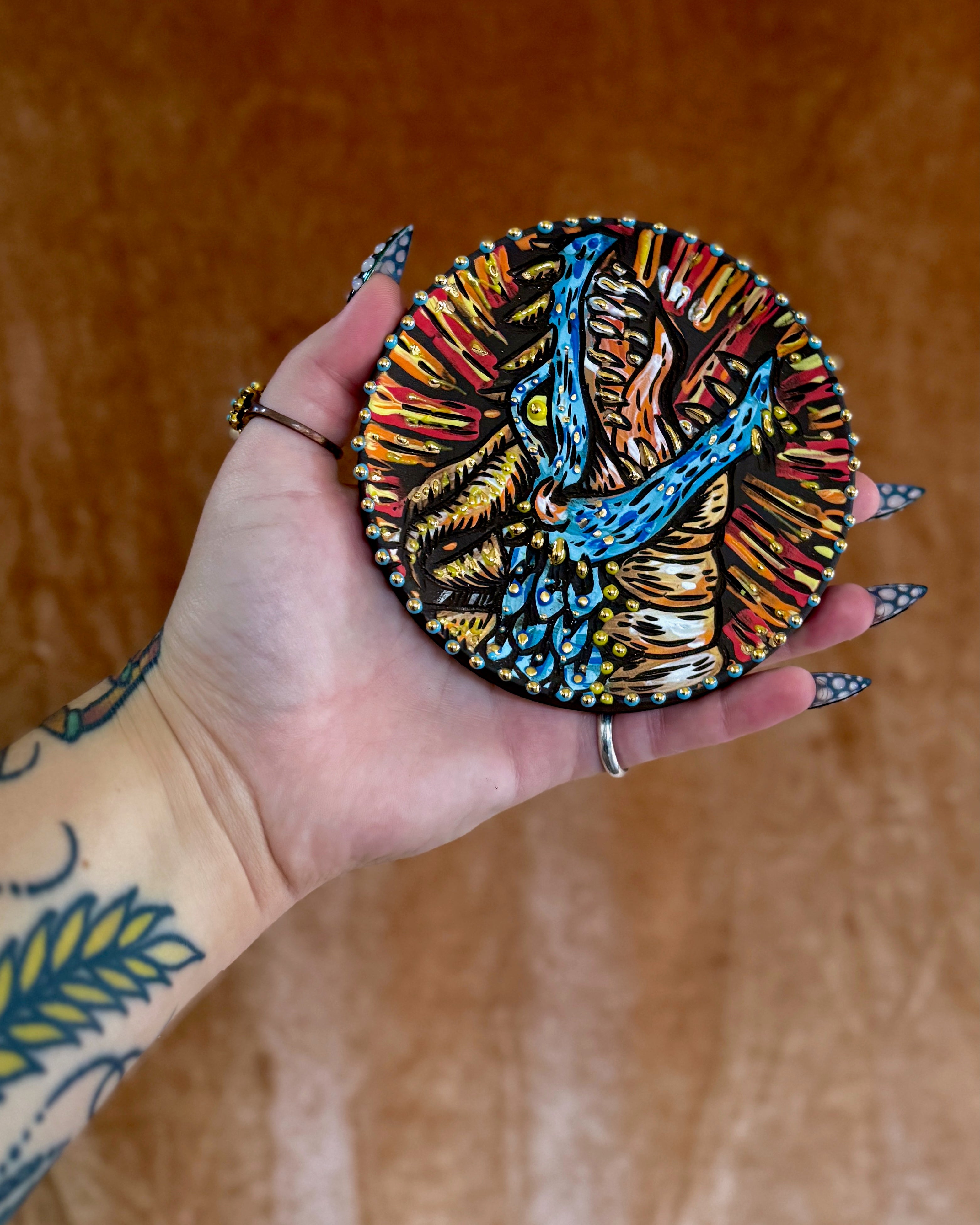 Handmade ceramic stoneware coaster with a smiling cartoon dragon design