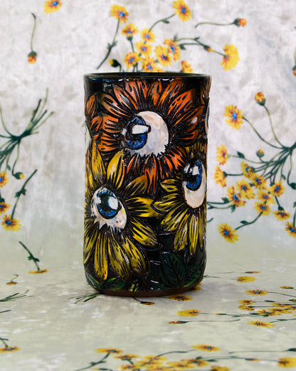 Handmade Ceramic cup with stylized eyeball flower designs in orange, yellow, and blue.