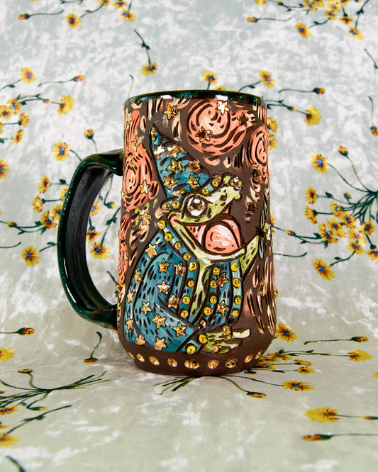 Black stoneware ceramic mug with a cartoon frog wizard design