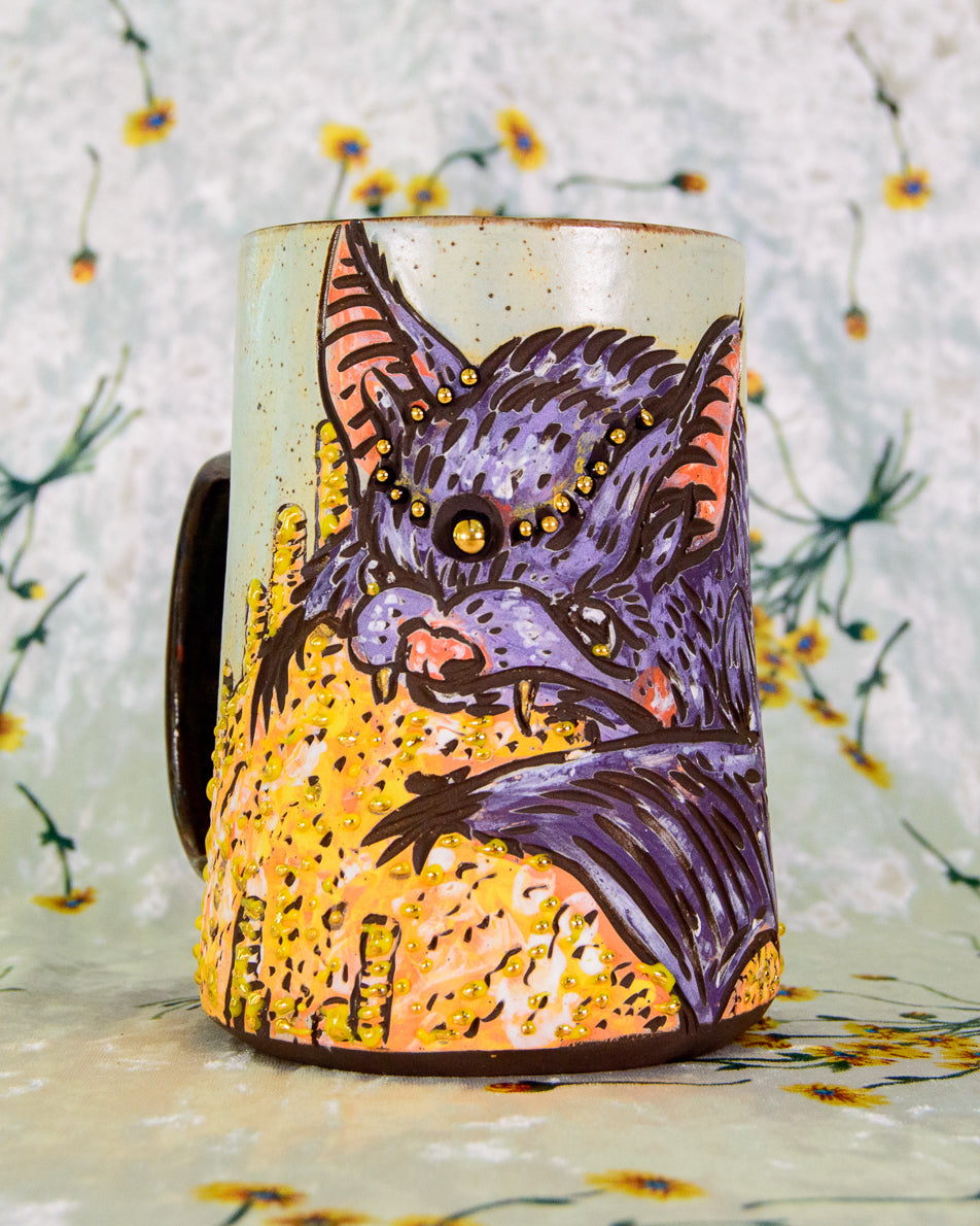 Handmade ceramic mug with a cute bat on a pile of gold