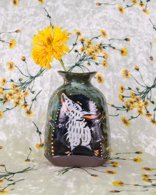 Decorative ceramic vase with a white bat design on a floral background