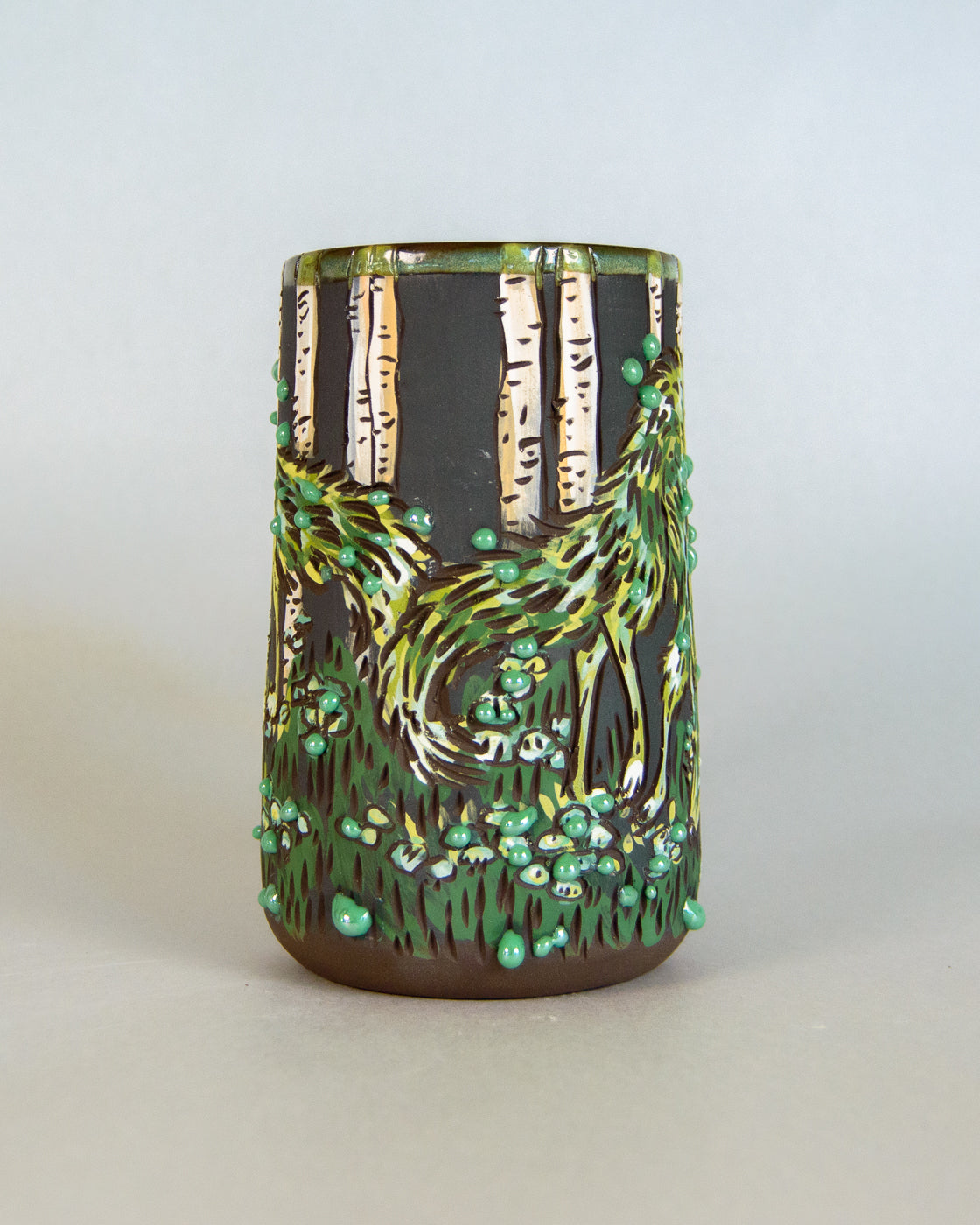 Ceramic tumbler with nature-themed design on a plain background