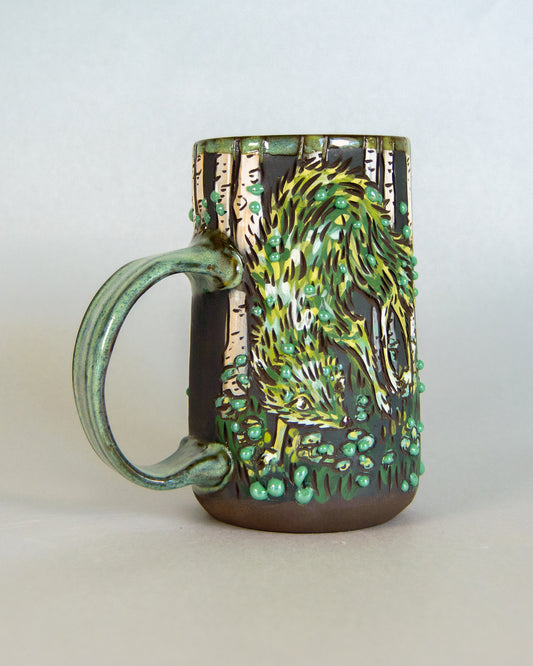 Ceramic mug with a green and brown  fox design on a white background
