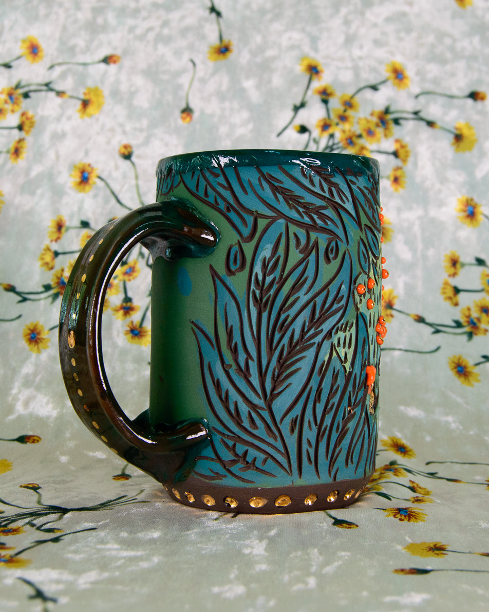 Green ceramic mug with brown handle on a floral background