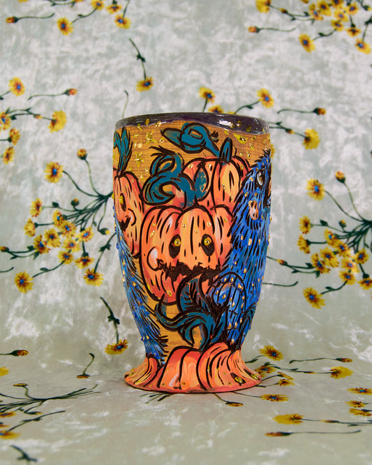 Colorful tumbler with a halloween crow and pumpkin design on a floral-patterned background