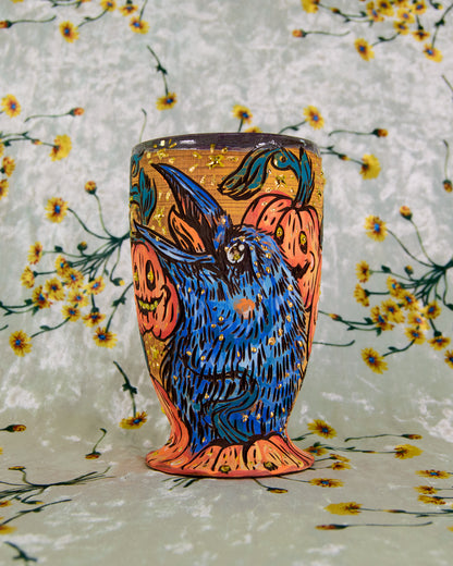 Intricate ceramic cup with a colorful crow and pumpkin design