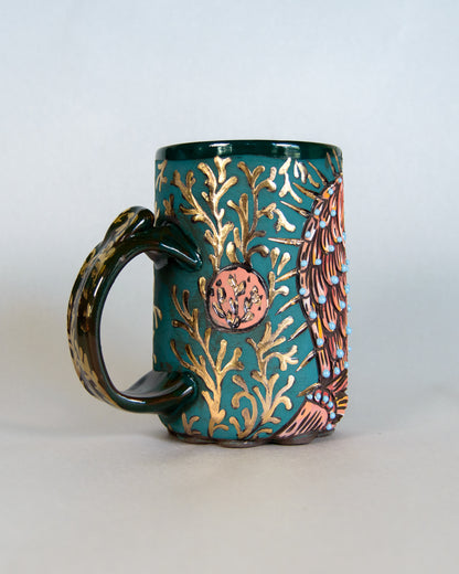 Ceramic mug with decorative gold leaf pattern on a white background