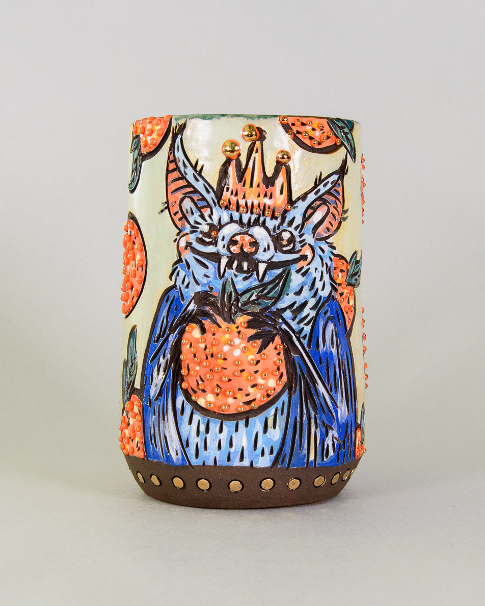 Handmade ceramic mug with a colorful bat and fruit design
