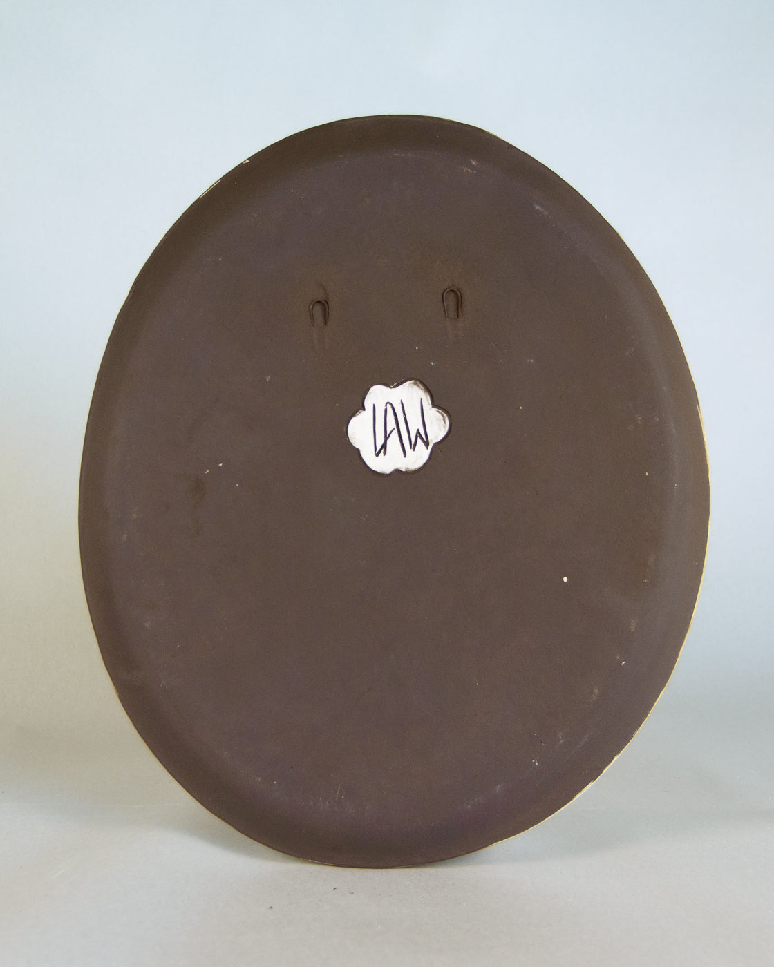 Round brown ceramic plate with a visible brand logo for lawful studios on a white background