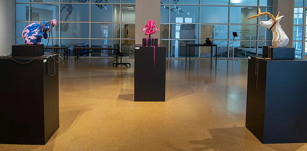 Modern art installation with sculptures in a glass-walled room.