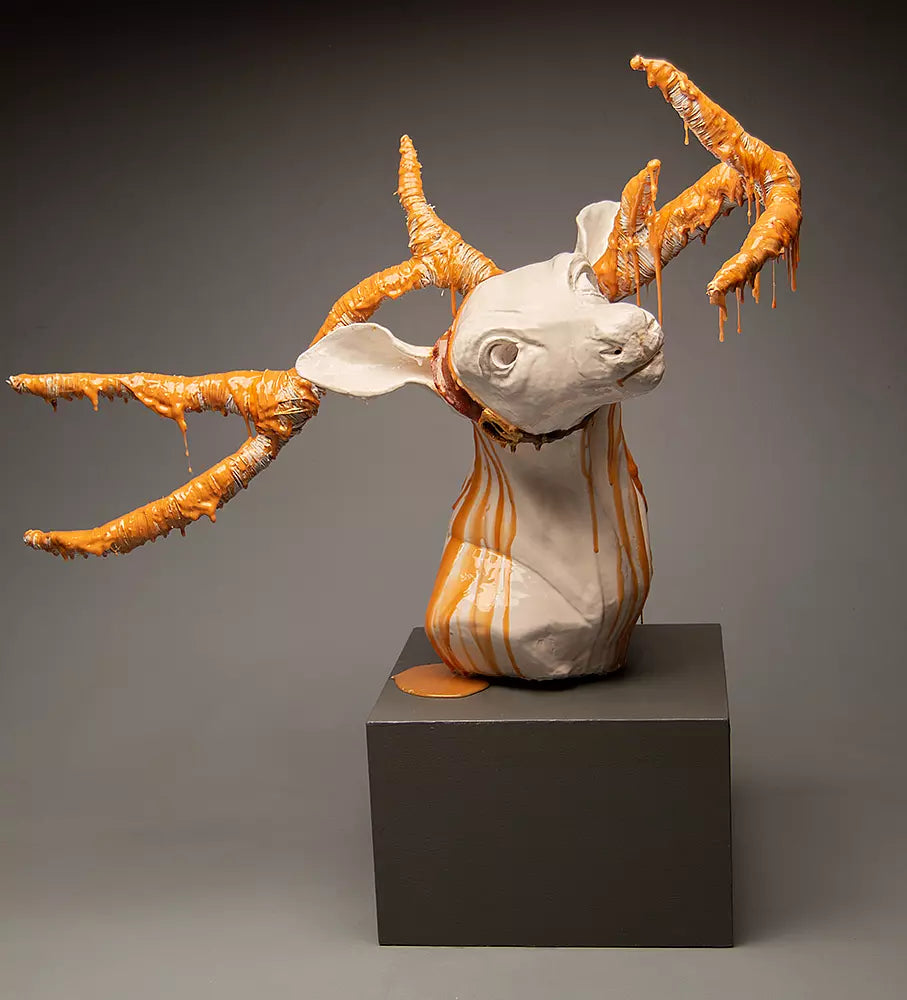 Ceramic sculpture of a deer wearing fake antlers dripping in gold epoxy resin