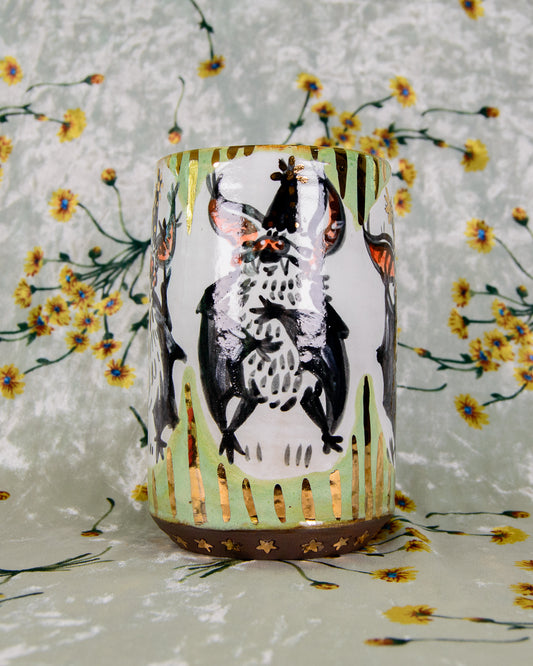 Ceramic mug with a black and white cartoon bat design and shiny gold details