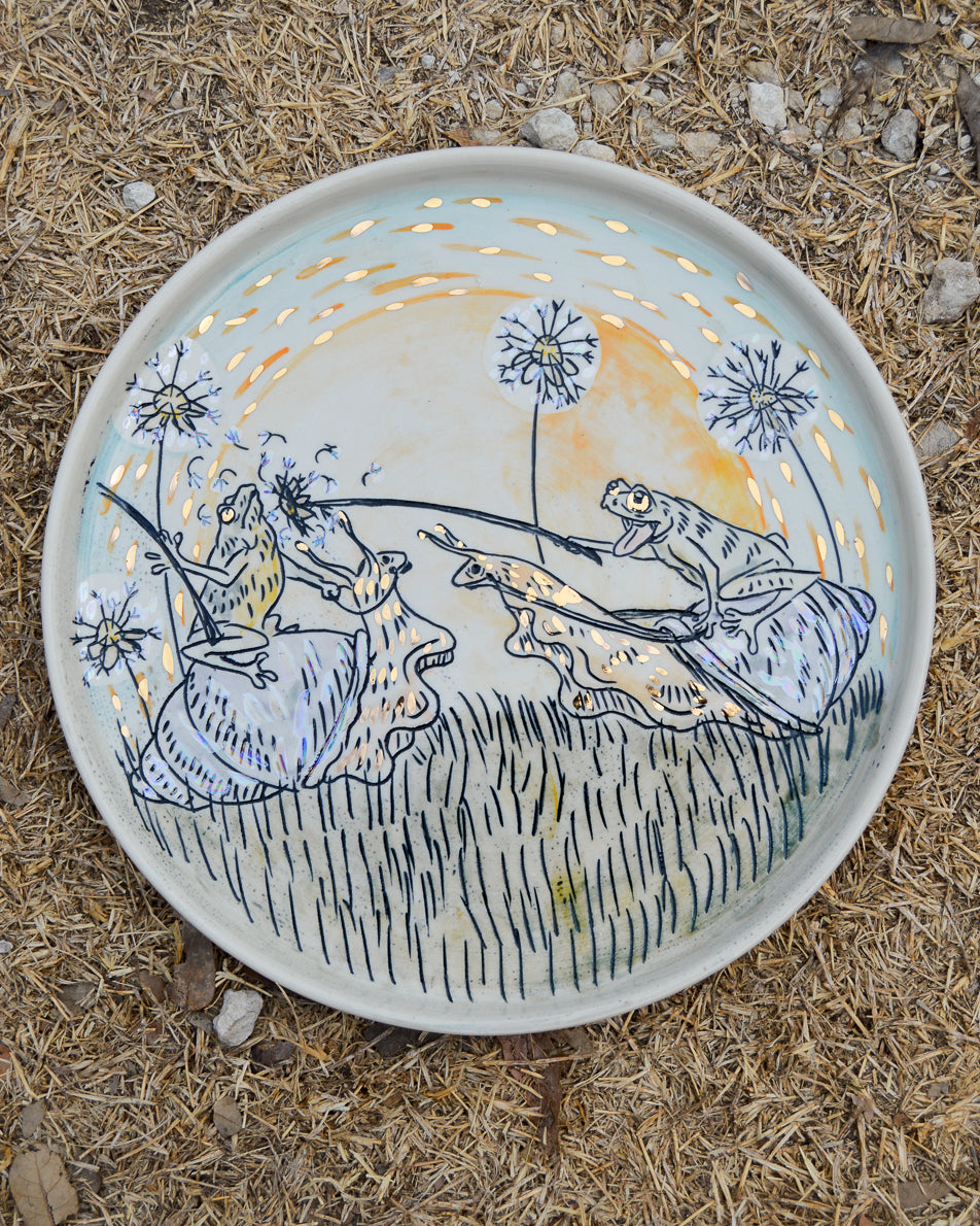 Ceramic plate with a design of two frogs playing and jousting with dandelions riding snails