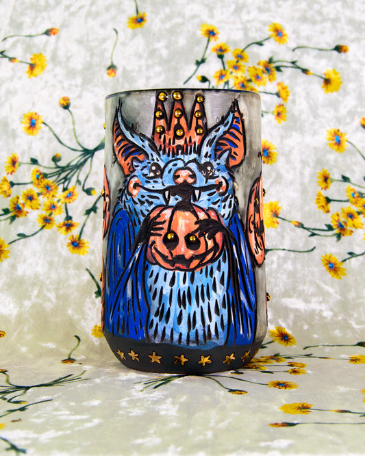 White ceramic mug with a halloween cartoon design of a blue bat wearing a crown with a pumpkin 