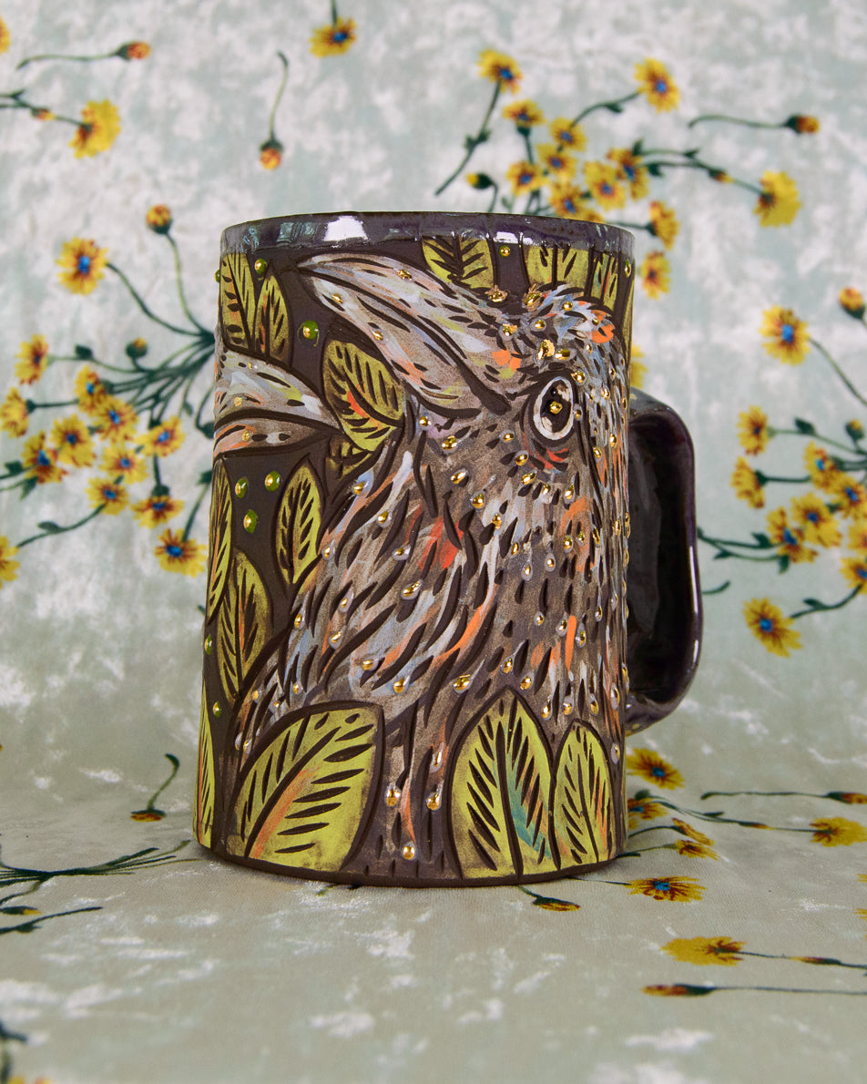 Mug with a hand painted crow design in purple and green