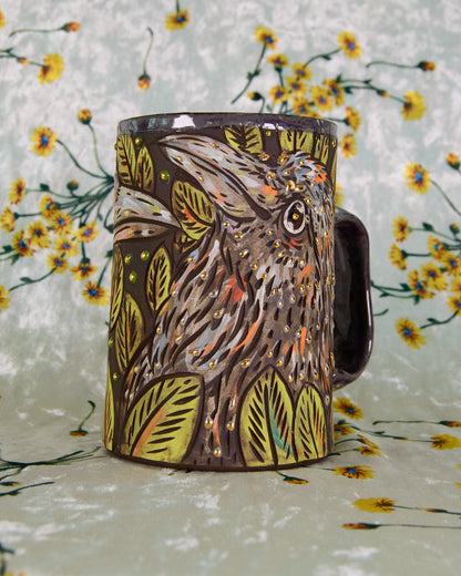 Mug with a hand painted crow design in purple and green