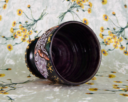 Ceramic cup with floral design on a floral-patterned fabric background