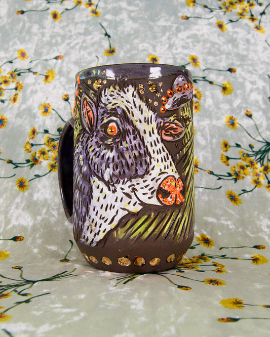 Black ceramic mug with a cartoon cow design and gold accents