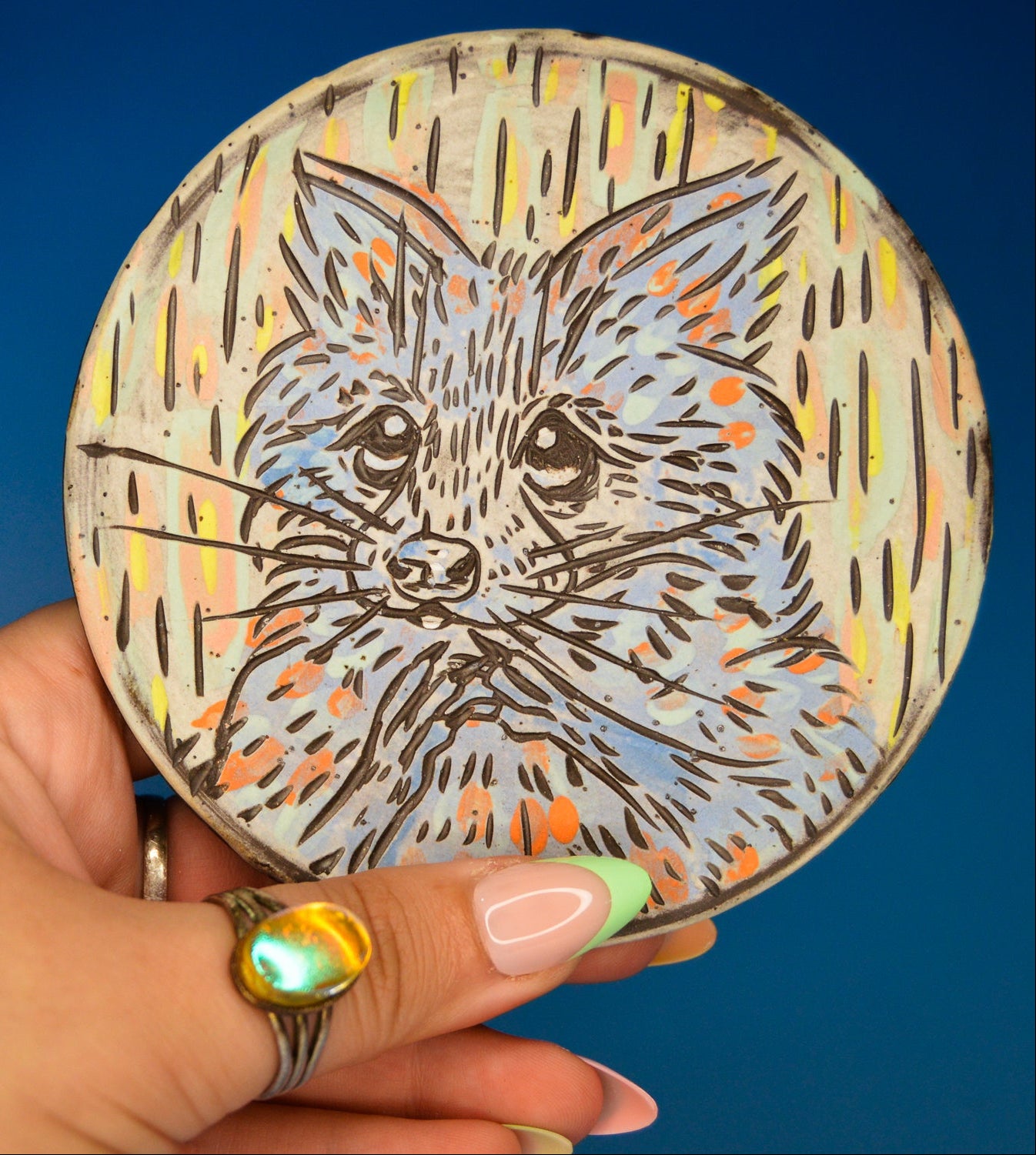 Handmade ceramic stoneware coaster with a cute pastel raccoon design