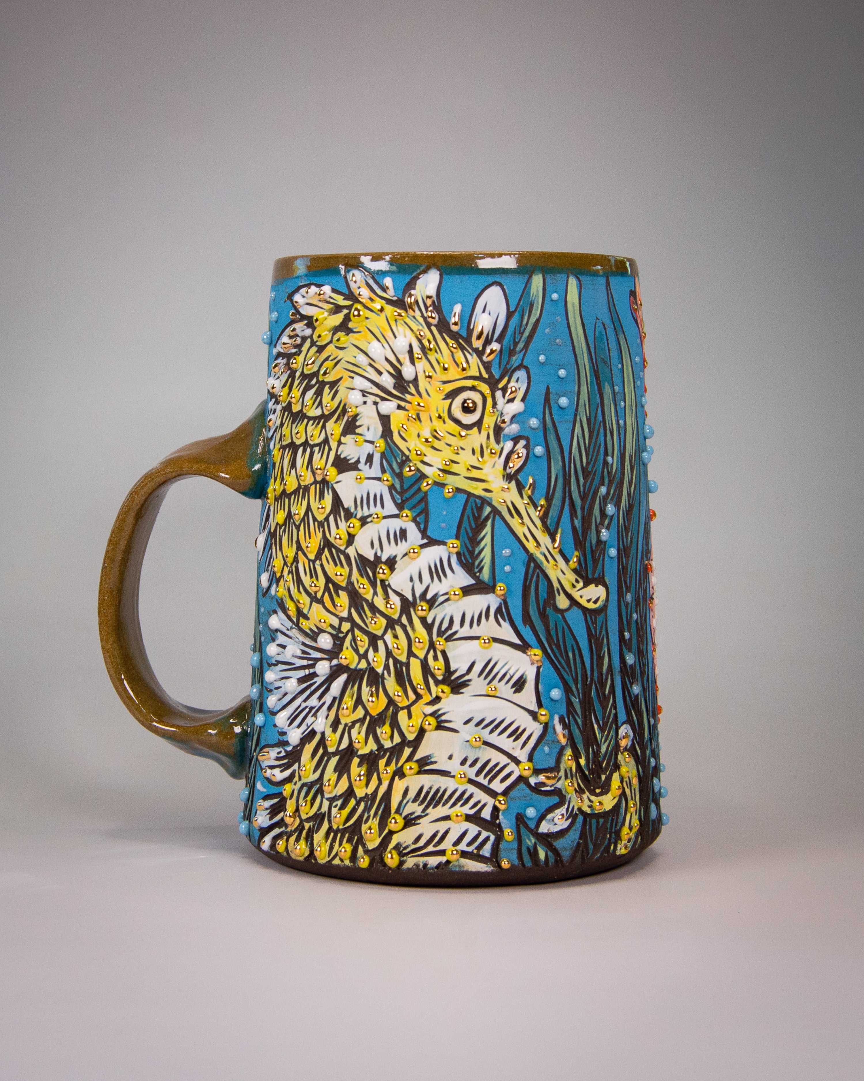 Handmade ceramic mug with a colorful yellow and blue seahorse design