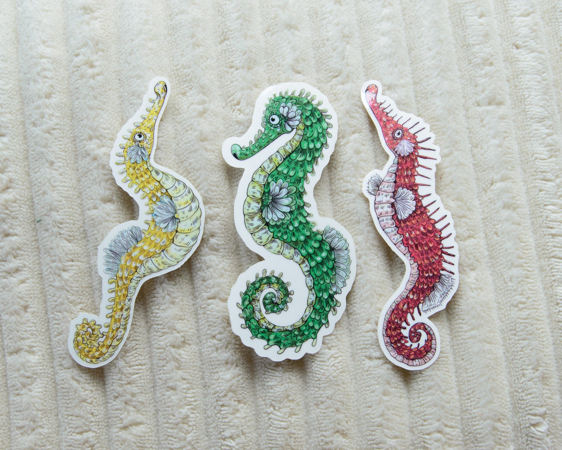 Three colorful and cute seahorse stickers in yellow, green, and red