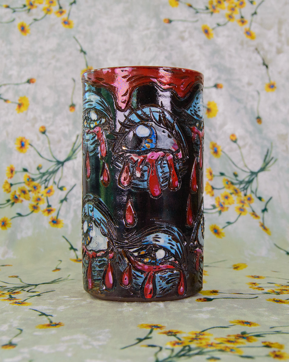 Ceramic highball cup decorated with crying blue and gold eyes on a floral background.