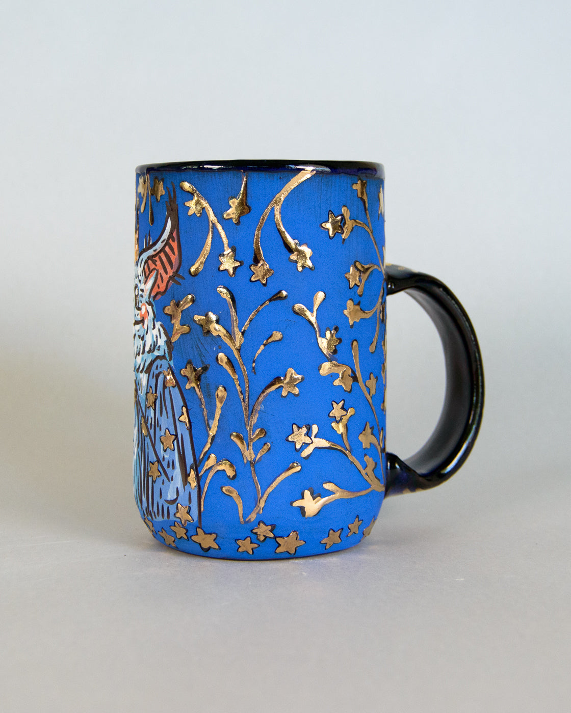 Blue mug with gold floral patterns on a light gray background