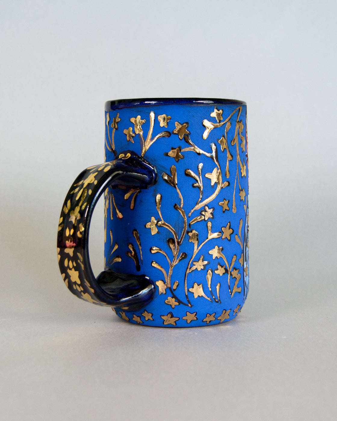 Blue mug with gold floral patterns on a white background