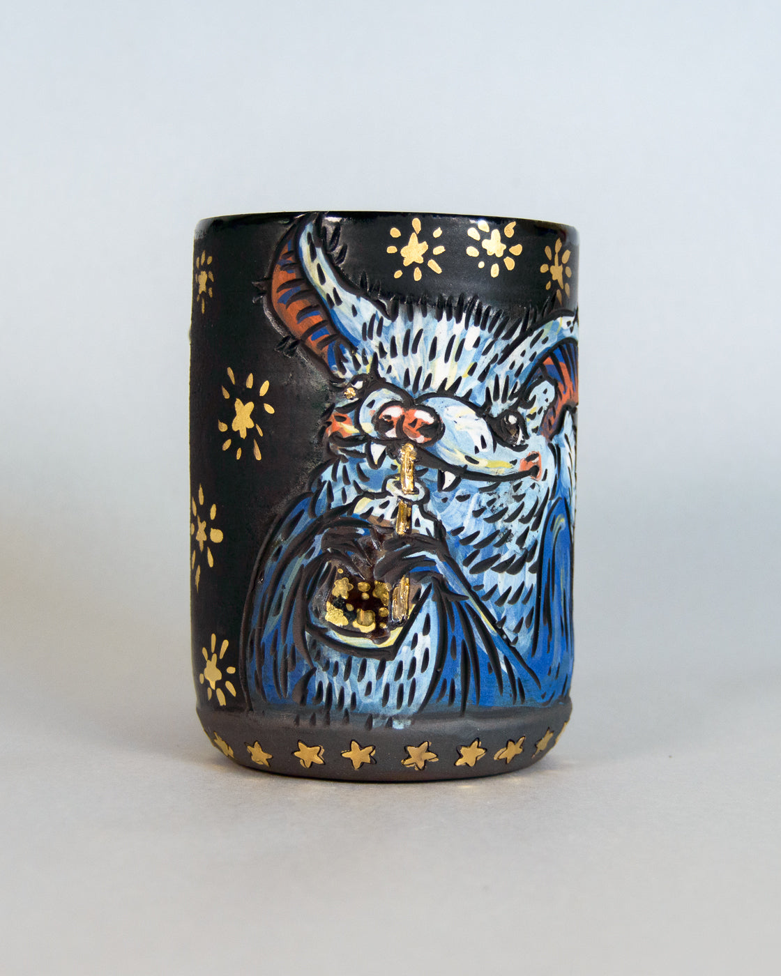 black mug with a cute blue bat design and gold star patterns
