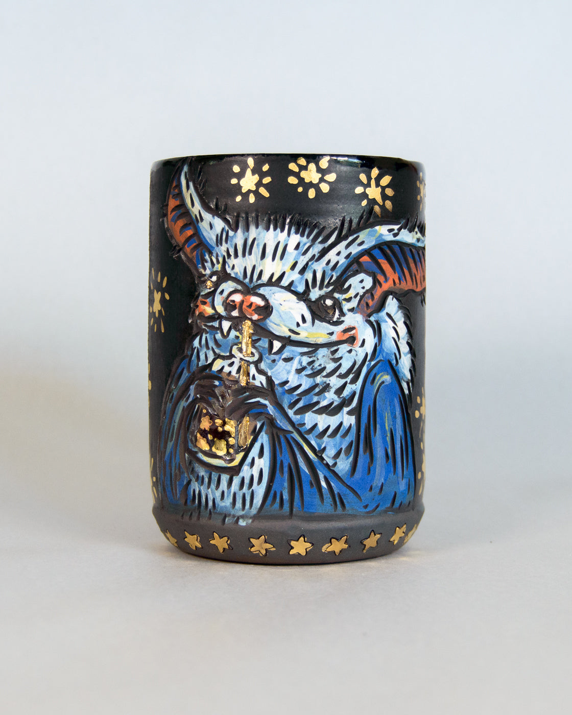 Ceramic mug with a colorful cute bat design and gold stars
