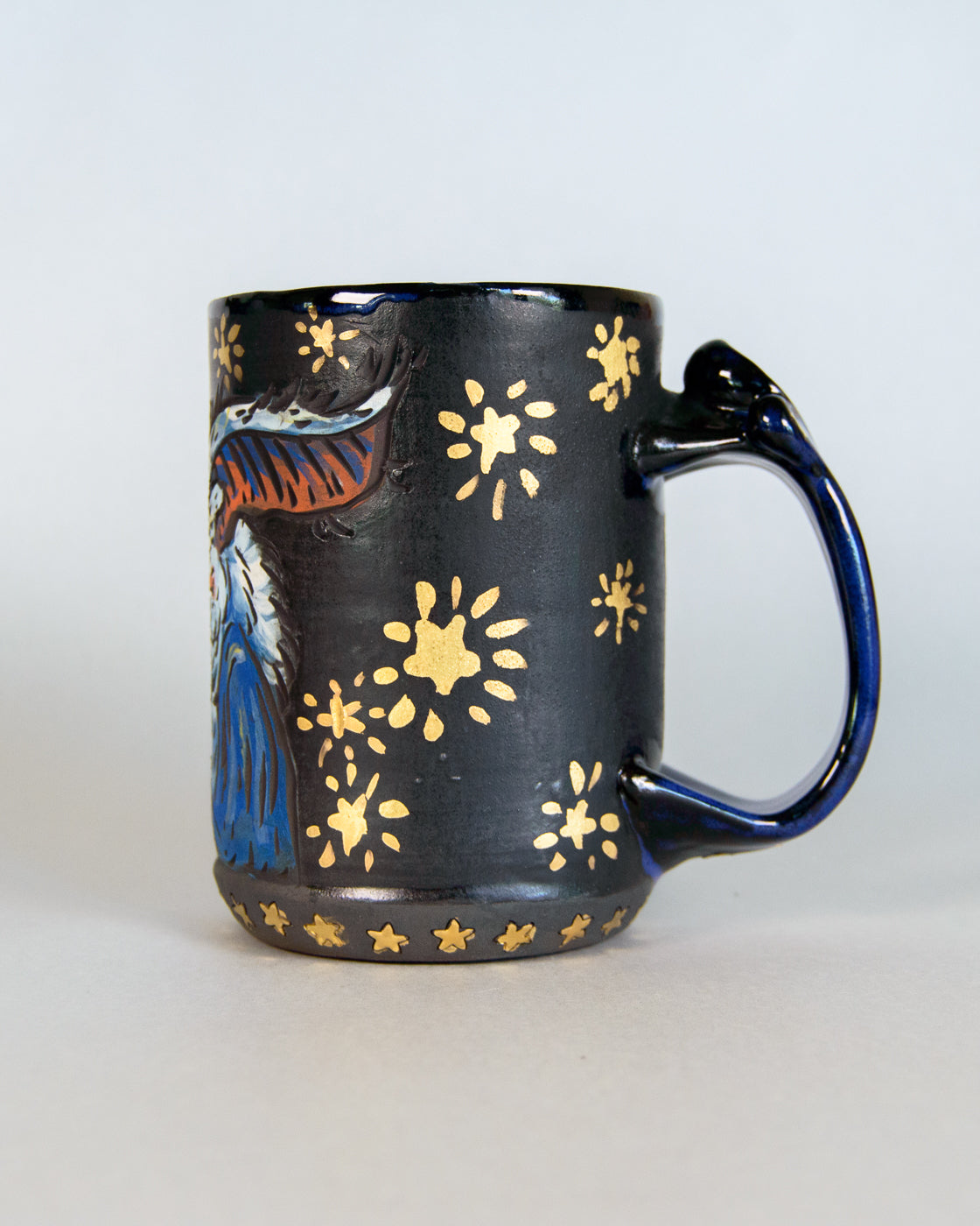Black mug with blue design and gold accents on a white background