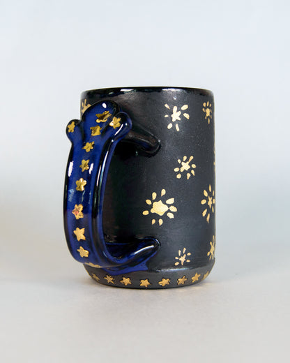 Black mug with gold star patterns on a white background
