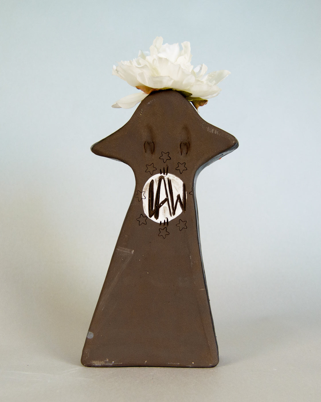 Decorative vase with a white flower on a light blue background