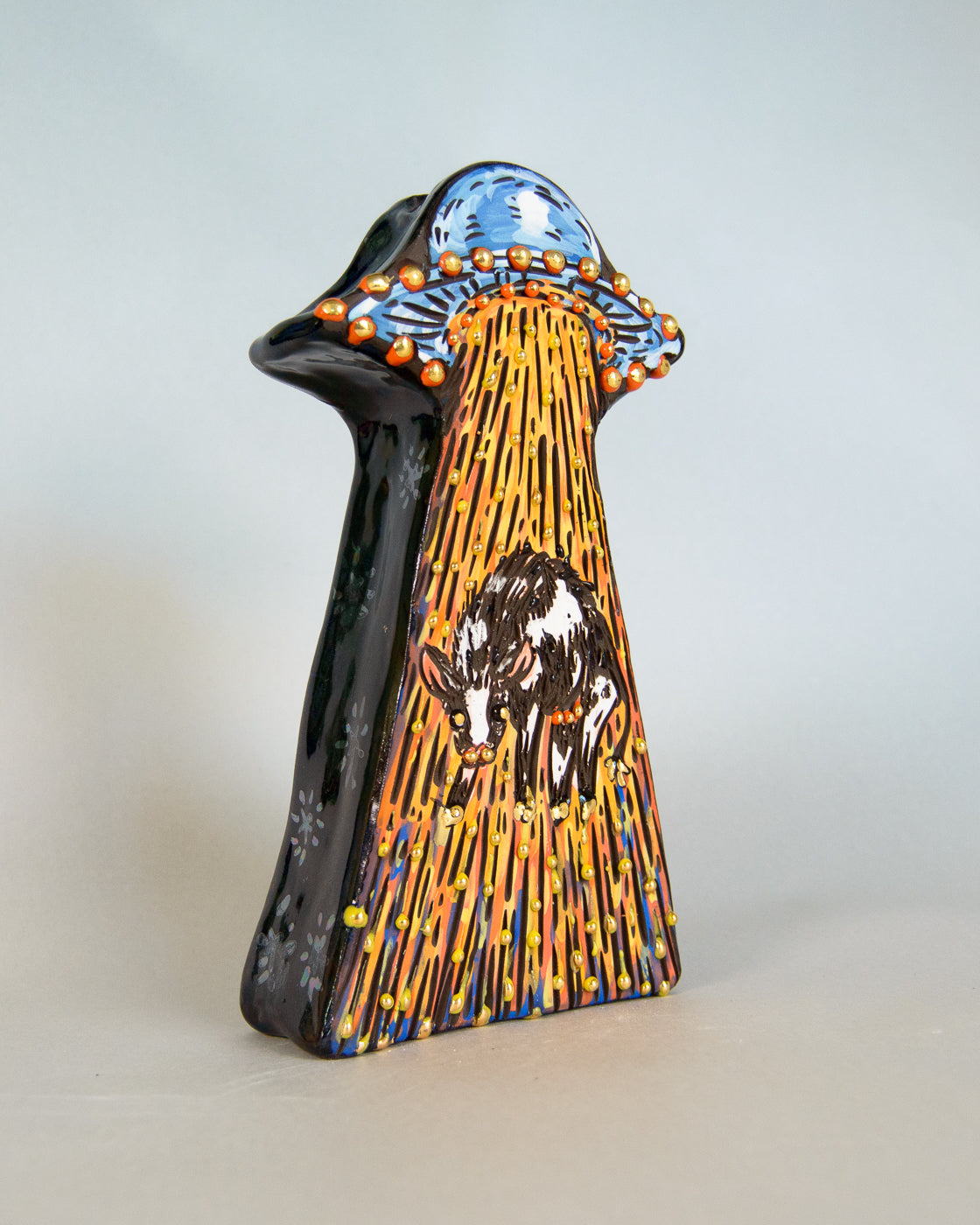 Decorative ceramic vase with artistic design of a cow and alien spaceship on a light gray background