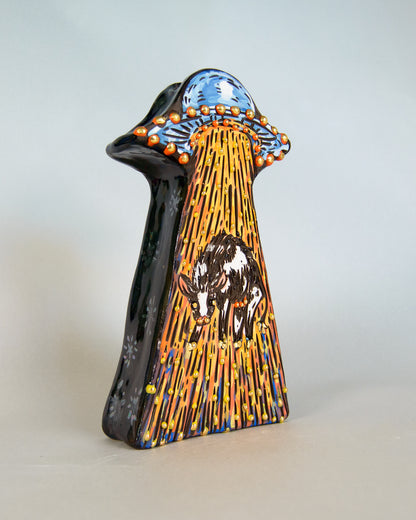 Decorative ceramic vase with artistic design of a cow and alien spaceship on a light gray background