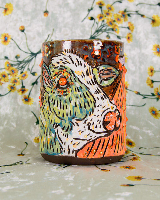 Ceramic mug with a colorful cow design on a floral background