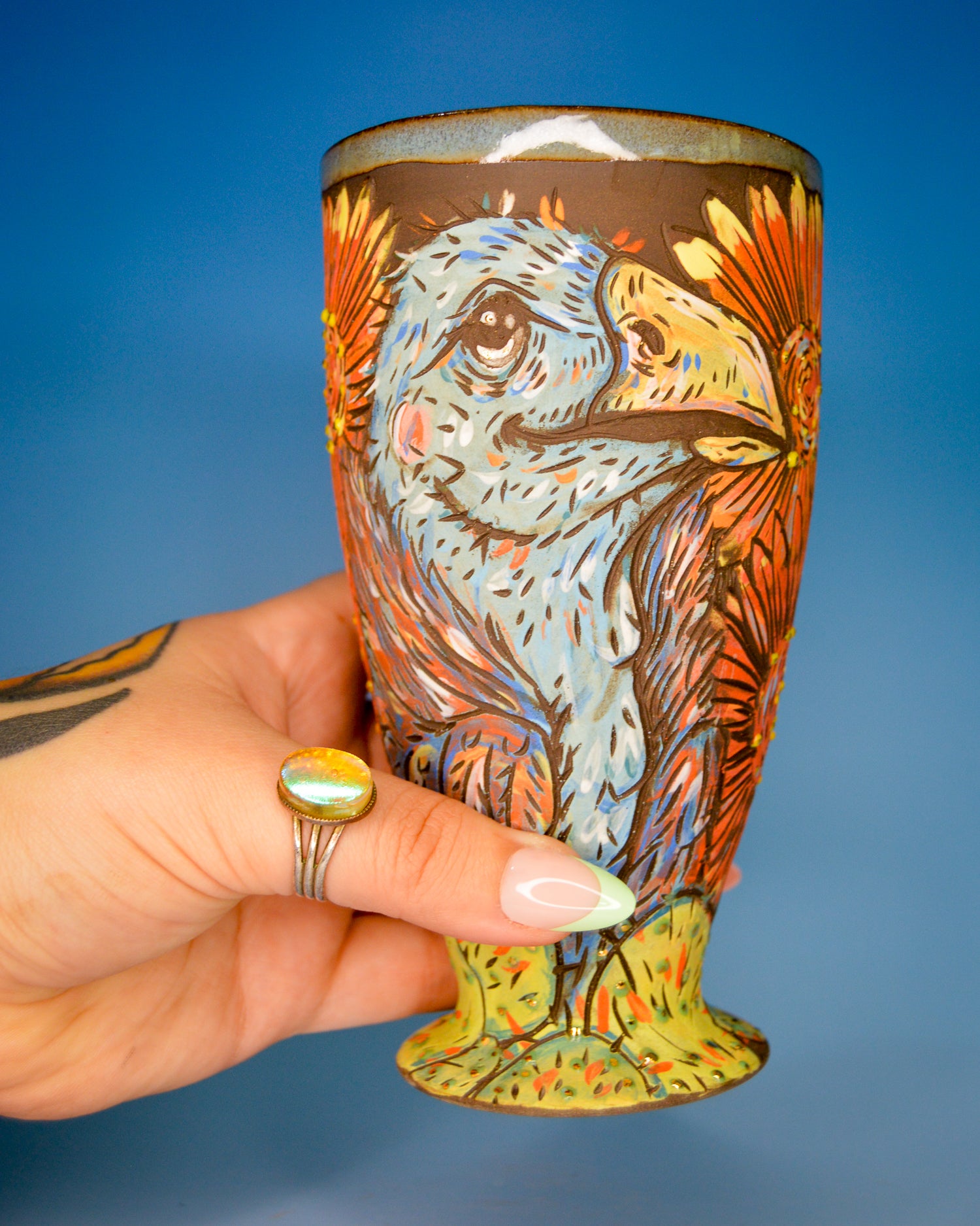 Handmade stoneware ceramic tumbler with a stylized blue vulture and cactus design