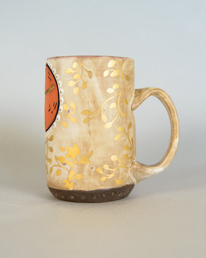 Ceramic mug with gold leaf design on a light gray background